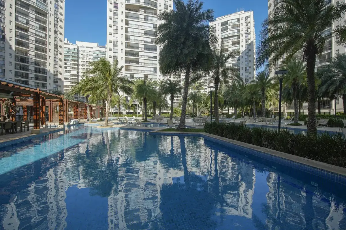 Piscina externa cercada por palmeiras
